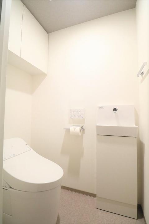 温水洗浄機能付きのトイレです。上部に吊戸棚があります。
